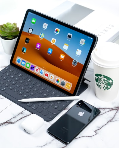 打开iPad旁边的太空灰iphonex和星巴克咖啡杯